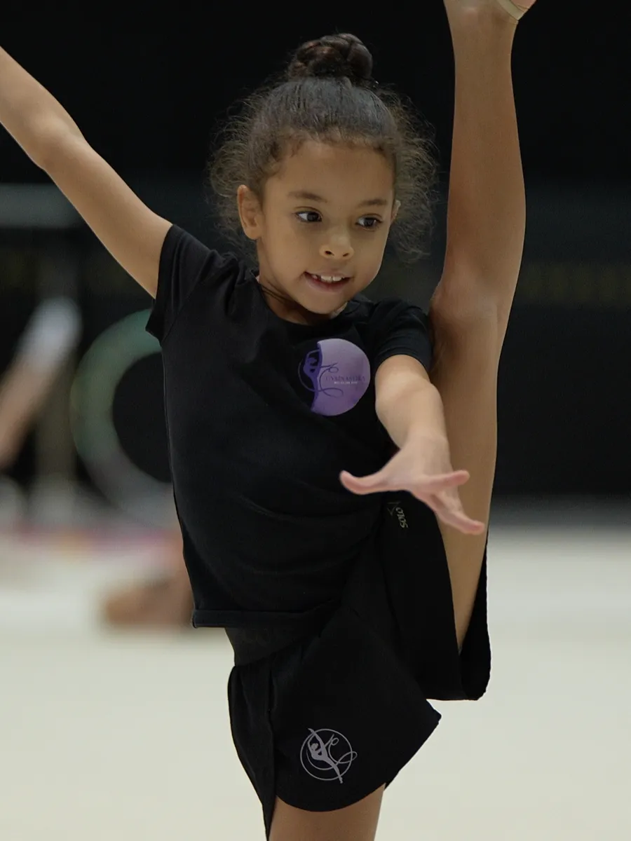 Young gymnast performing an element on the floor at a GYMNASTIKA gym